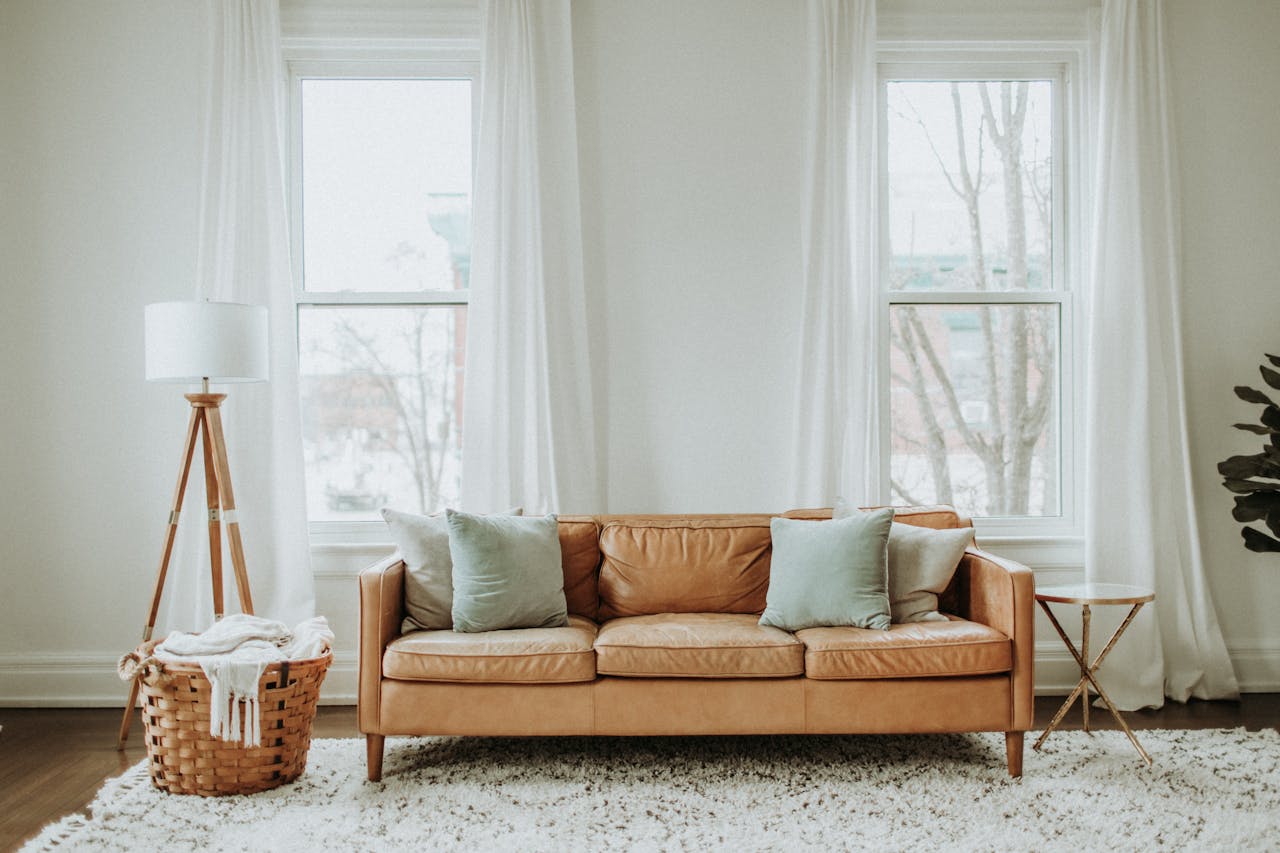 Livingroom, leather sofa, white curtains. Image by Pexels