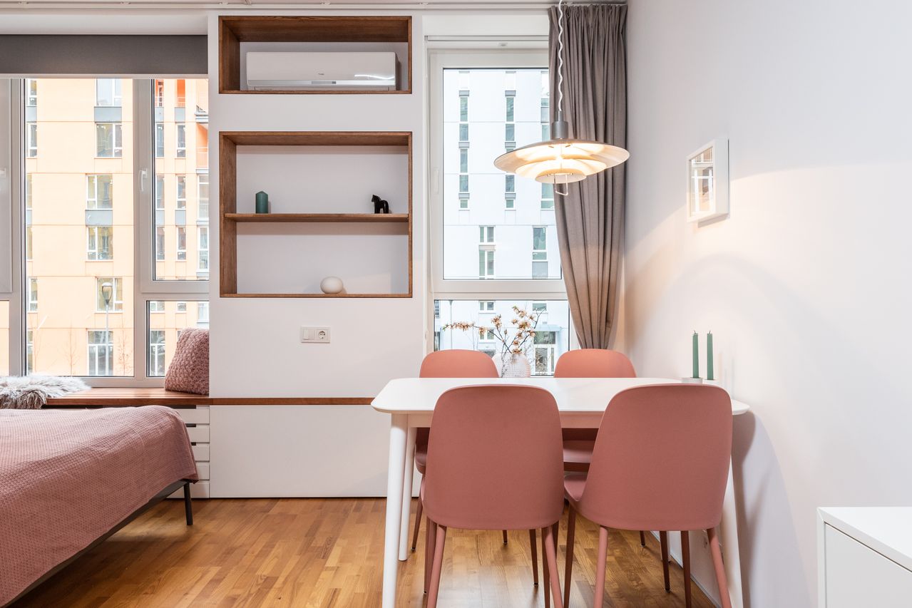 A wood dining table in a small bright apartment with light streaming through the window. Photo by Max Vakhtbovych on Pexels
