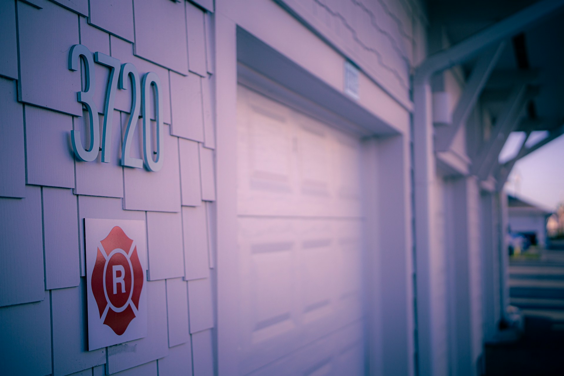 House number 3720 displayed on a shingled wall next to a garage with a secure entryway. Image via Unsplash