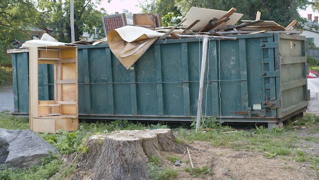 A green dumpster filled with construciton materials