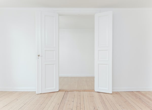 Two white doors open, hardwood floors