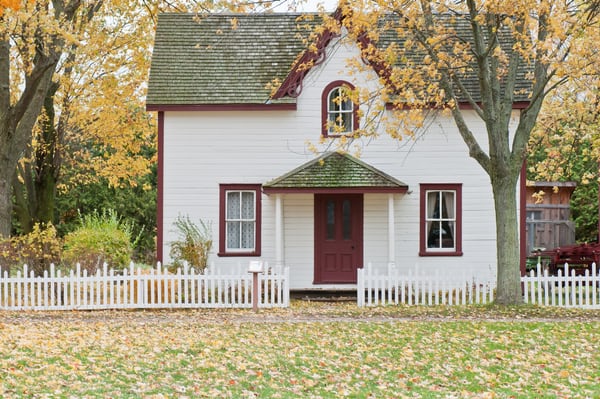 White house with red trim. Lots of leaves falling