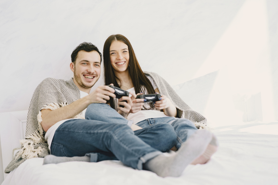 Two people gaming from the bed