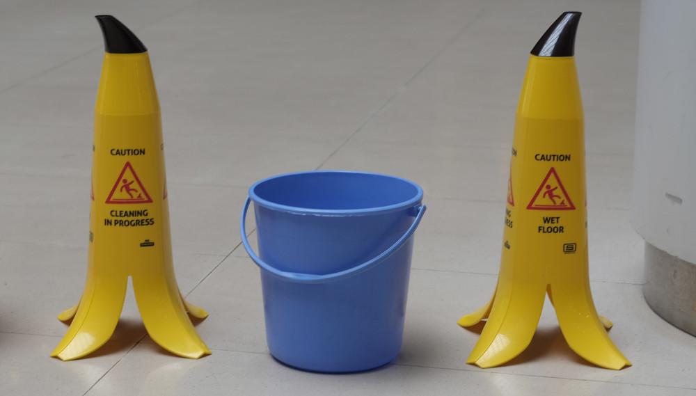 a blue bucket between a yellow wet floor signs on the floor