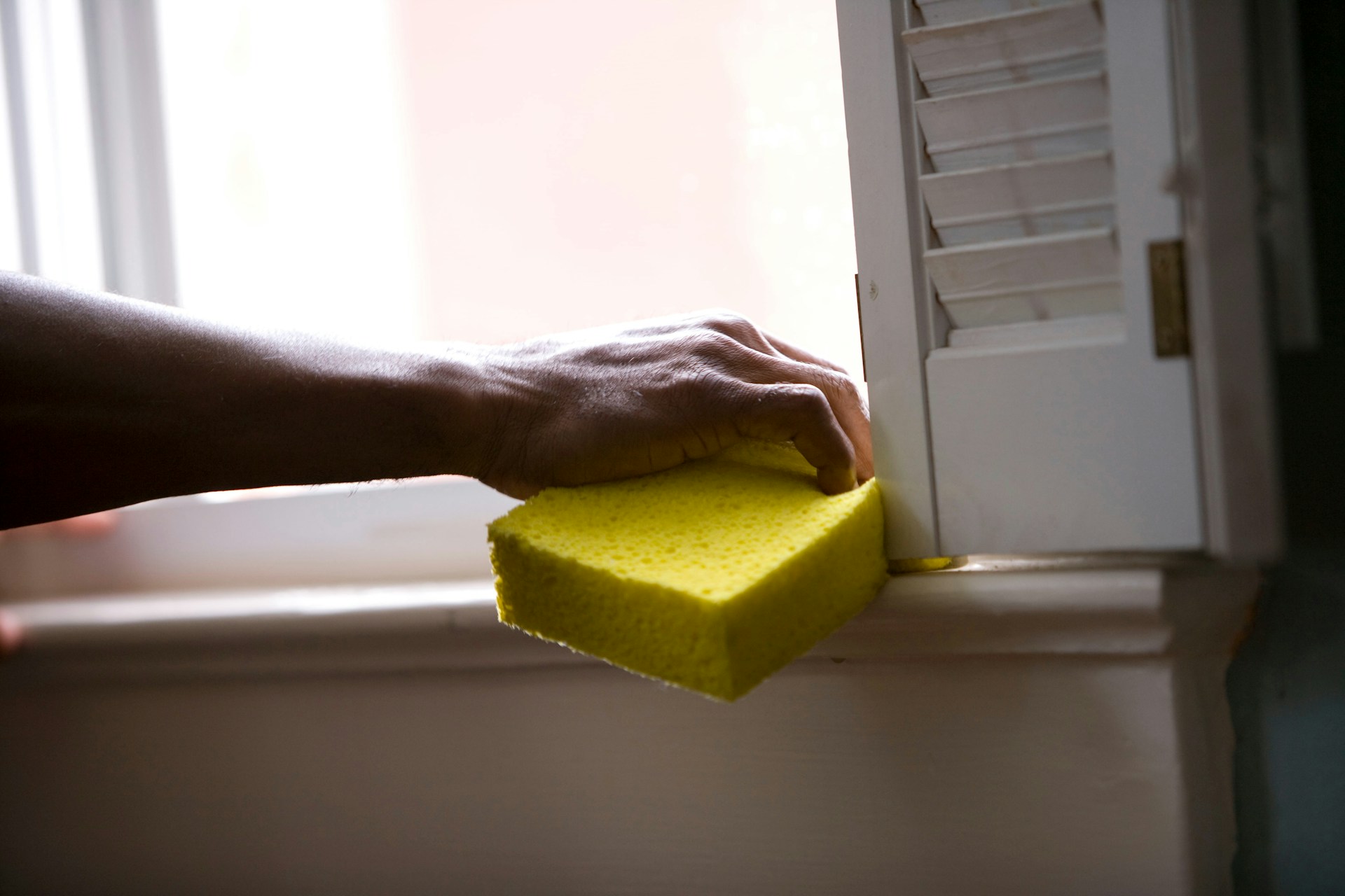 Person using a yellow sponge to clean