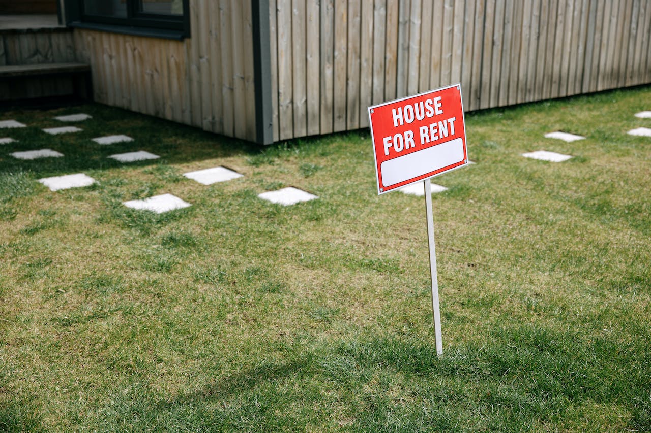 red sign house for rent on a lawn