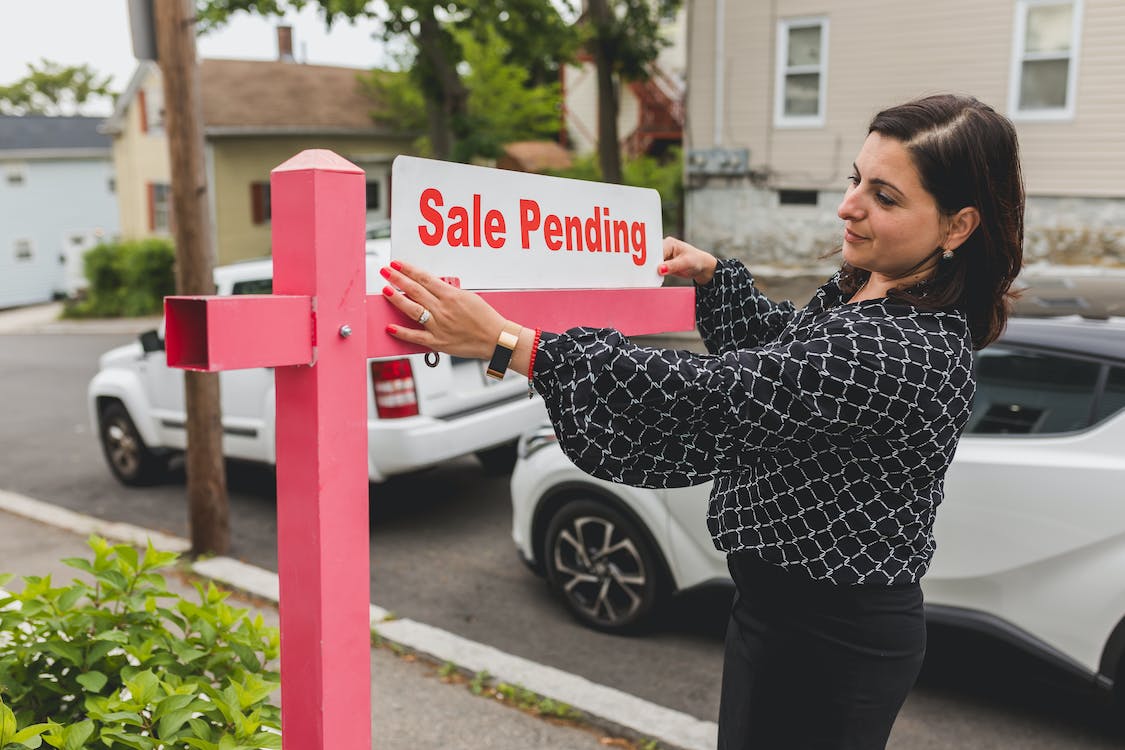 Person putting up a sale pending sign
