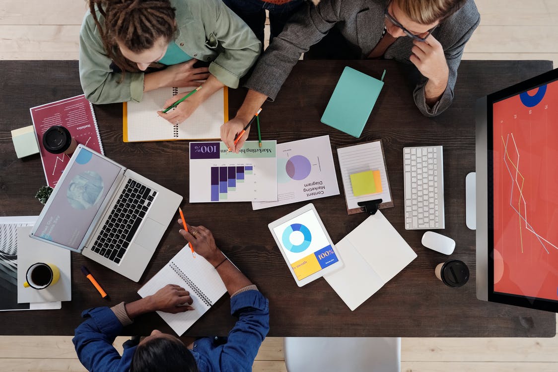 people gathered around a table, paper, computers on the table