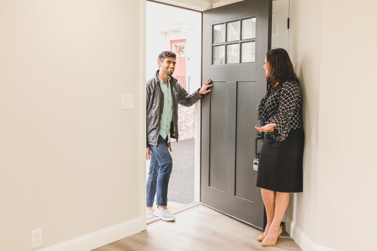 Women greeting a man at a door. Image by Pexels