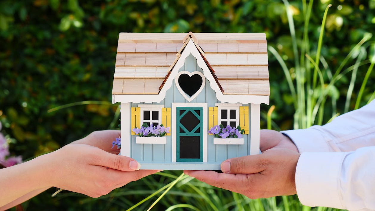 Two people holding a wooden house