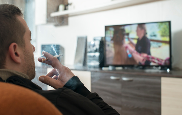 person smoking in front of a TV