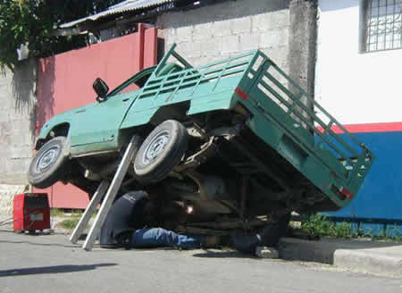 person working on a car unsafely