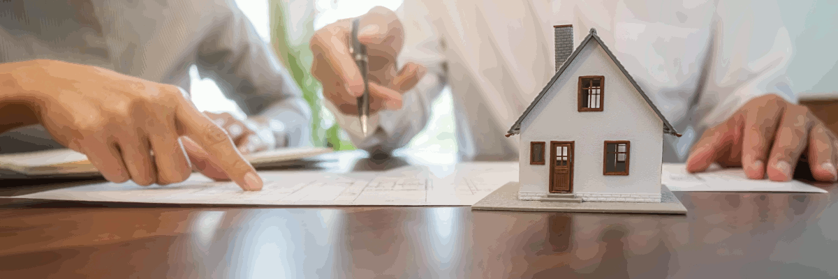 Small house n a table, paperwork, pen, hands