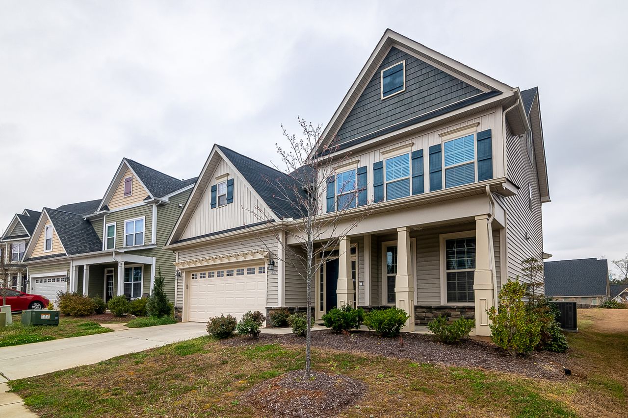 A row of modern suburban homes with garages, driveways, and landscaped lawns in daylight. Image by Pexels