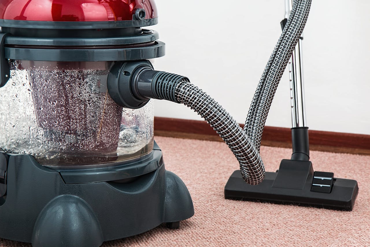 Black and red cannister vacuum cleaner. Image by Pexels