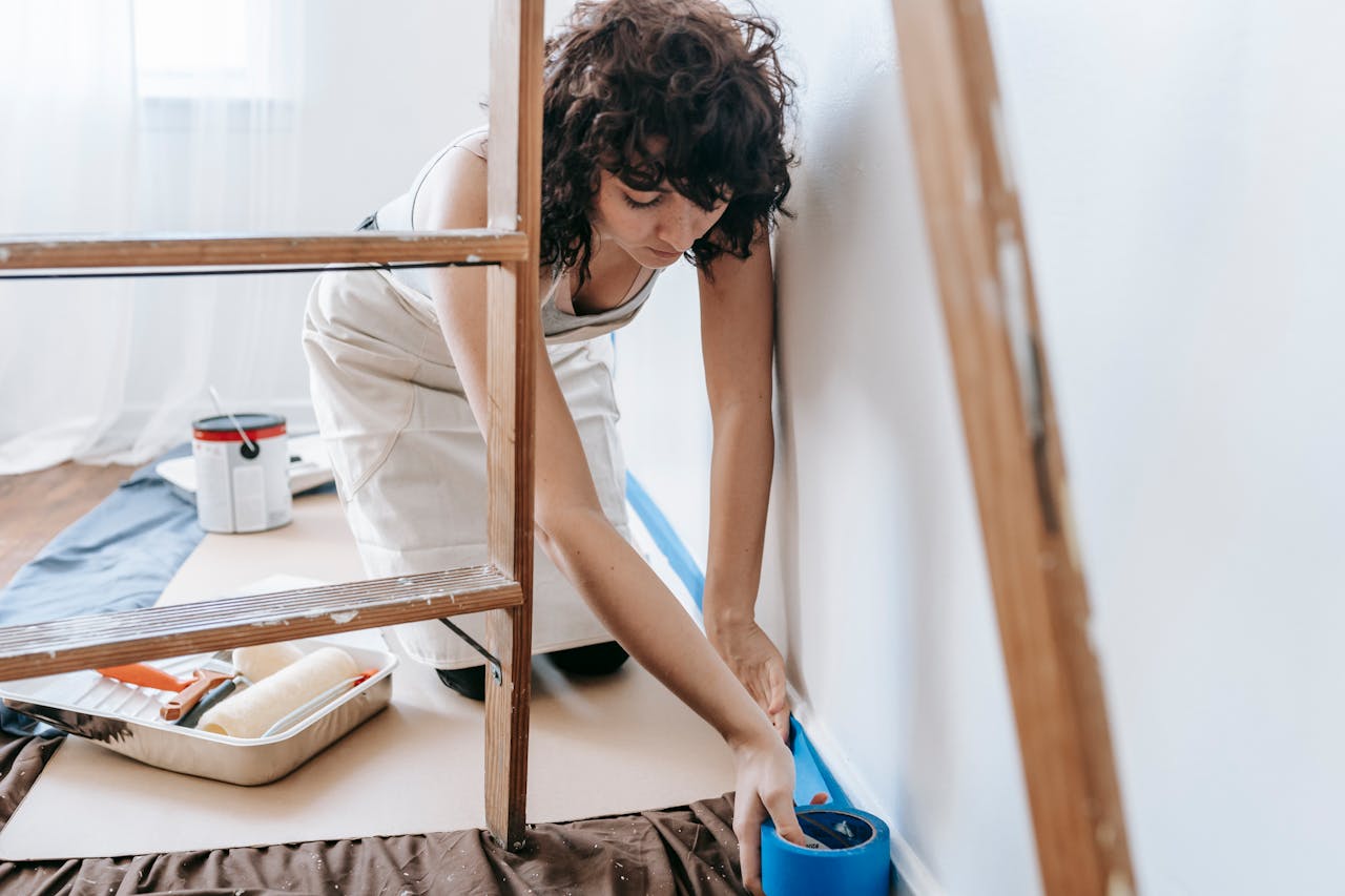 Person putting tape on a wall. Image by Pexels