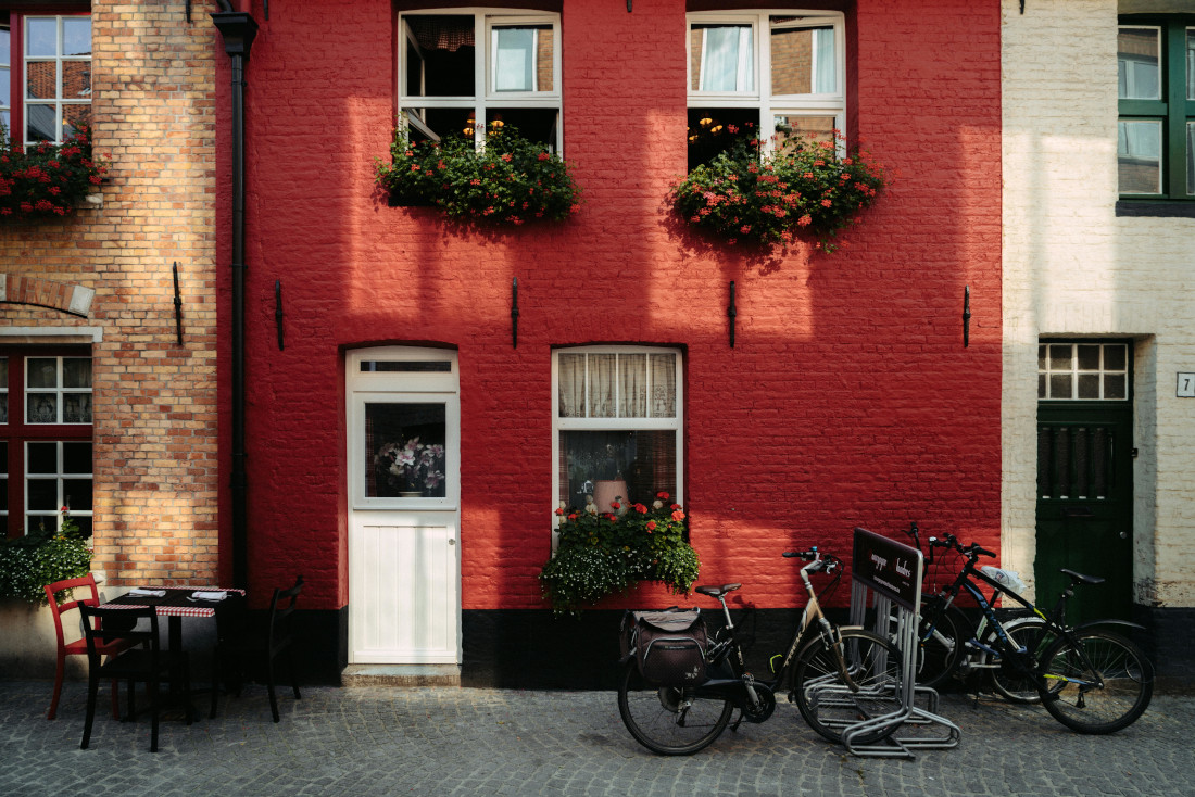 Townhouse with multiple colors, bikes and a table with chairs in front. Image by Pexels