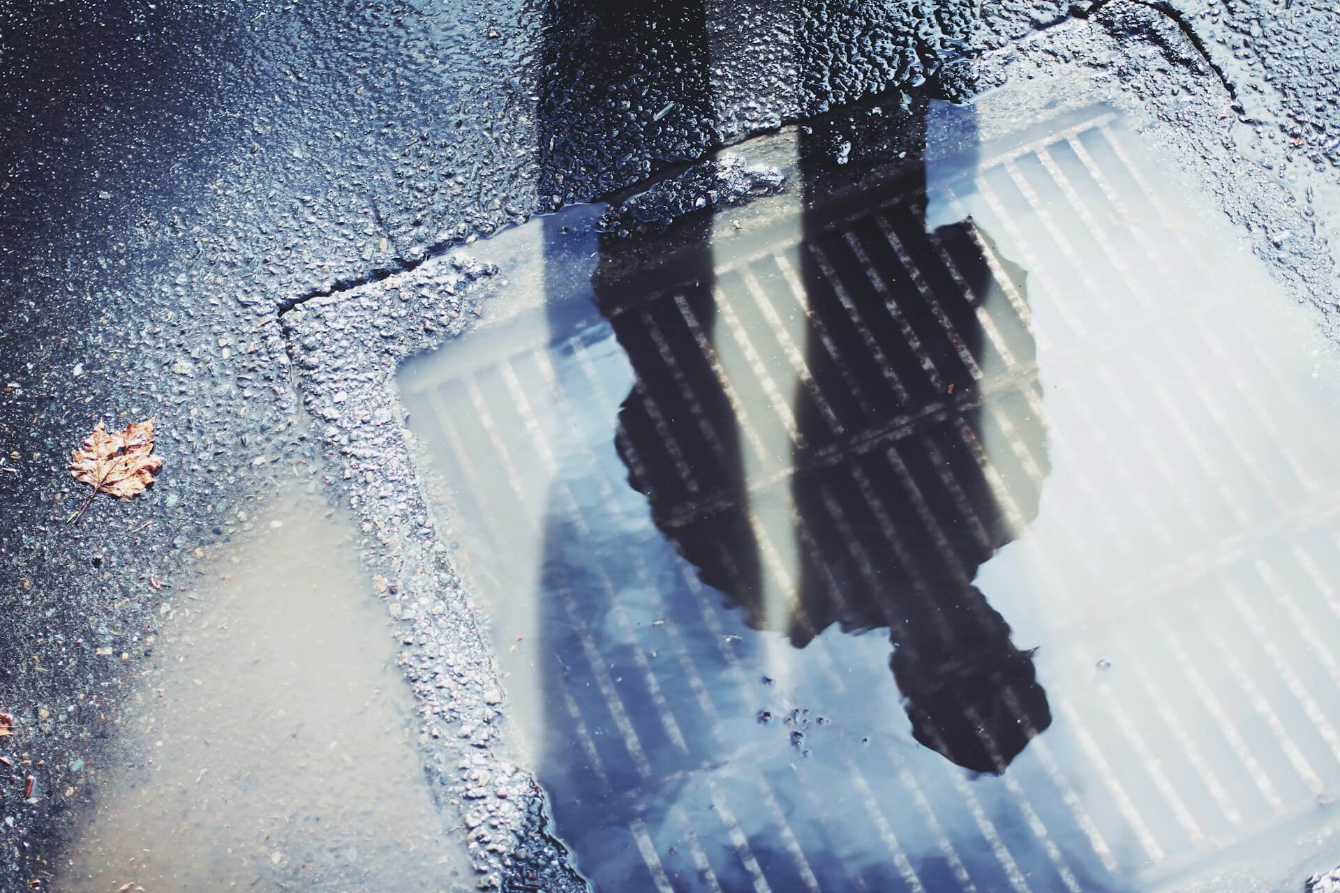 white and black concrete ground. Puddle, shaddow of a person. Image by Unsplash