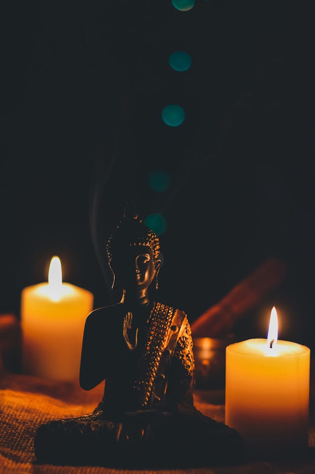 Sitting Buddah next to candles. Image by Unsplash