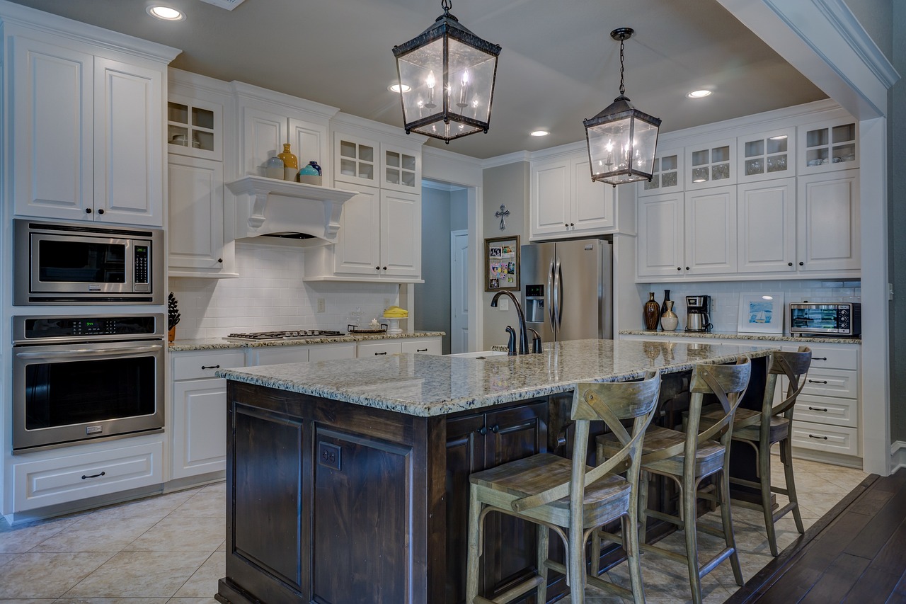 White kitchen cabinets, brown island, chairs. Image by Pixabay