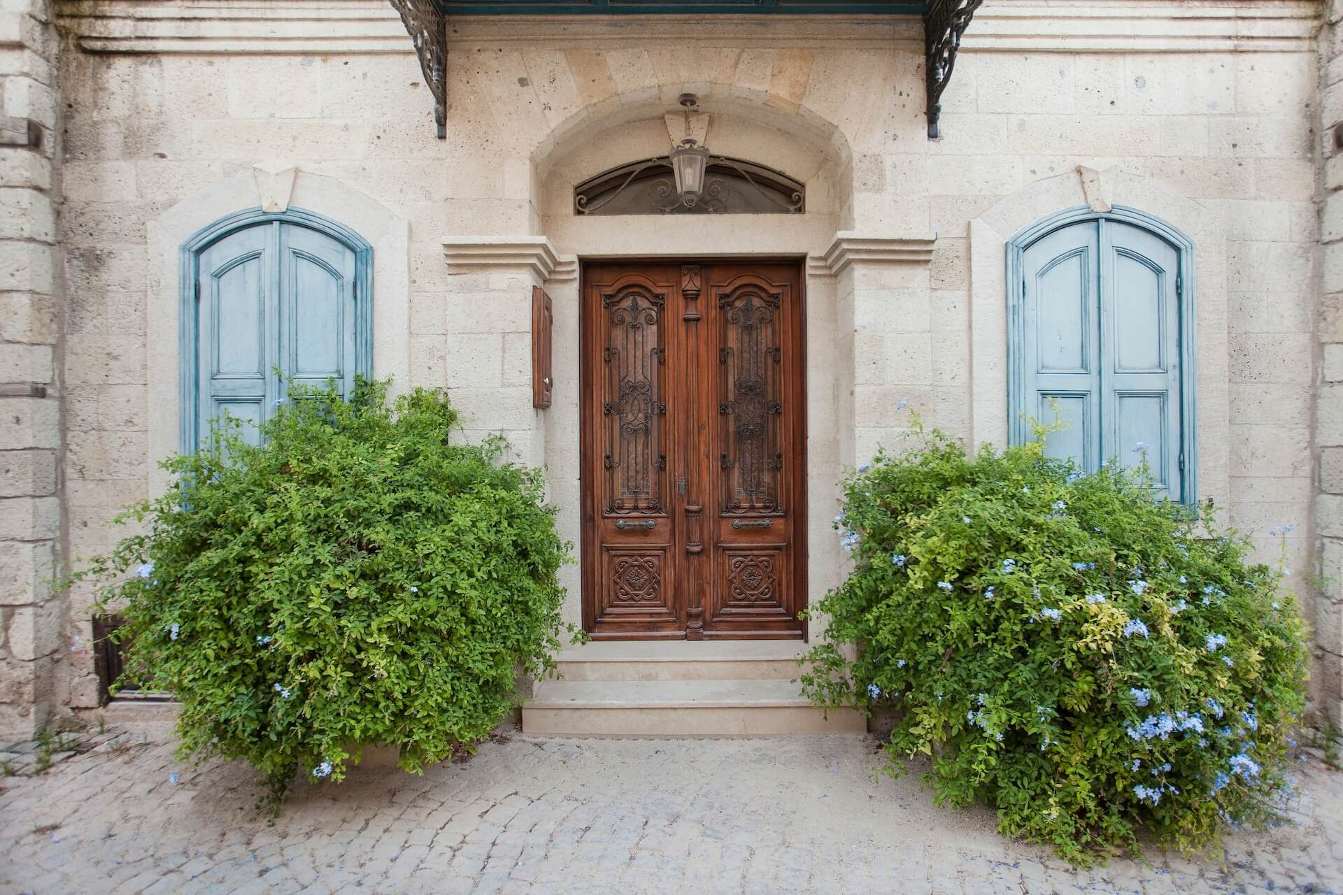 carved wooden door on a white house with blue shudders