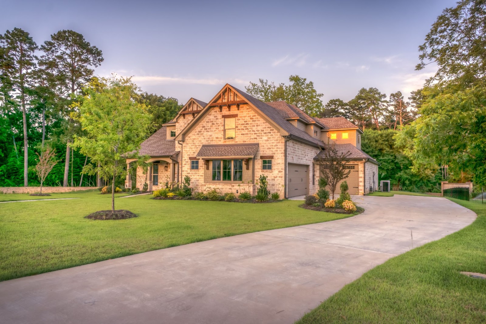 brick house, blue sky, trees around the house, long drivway