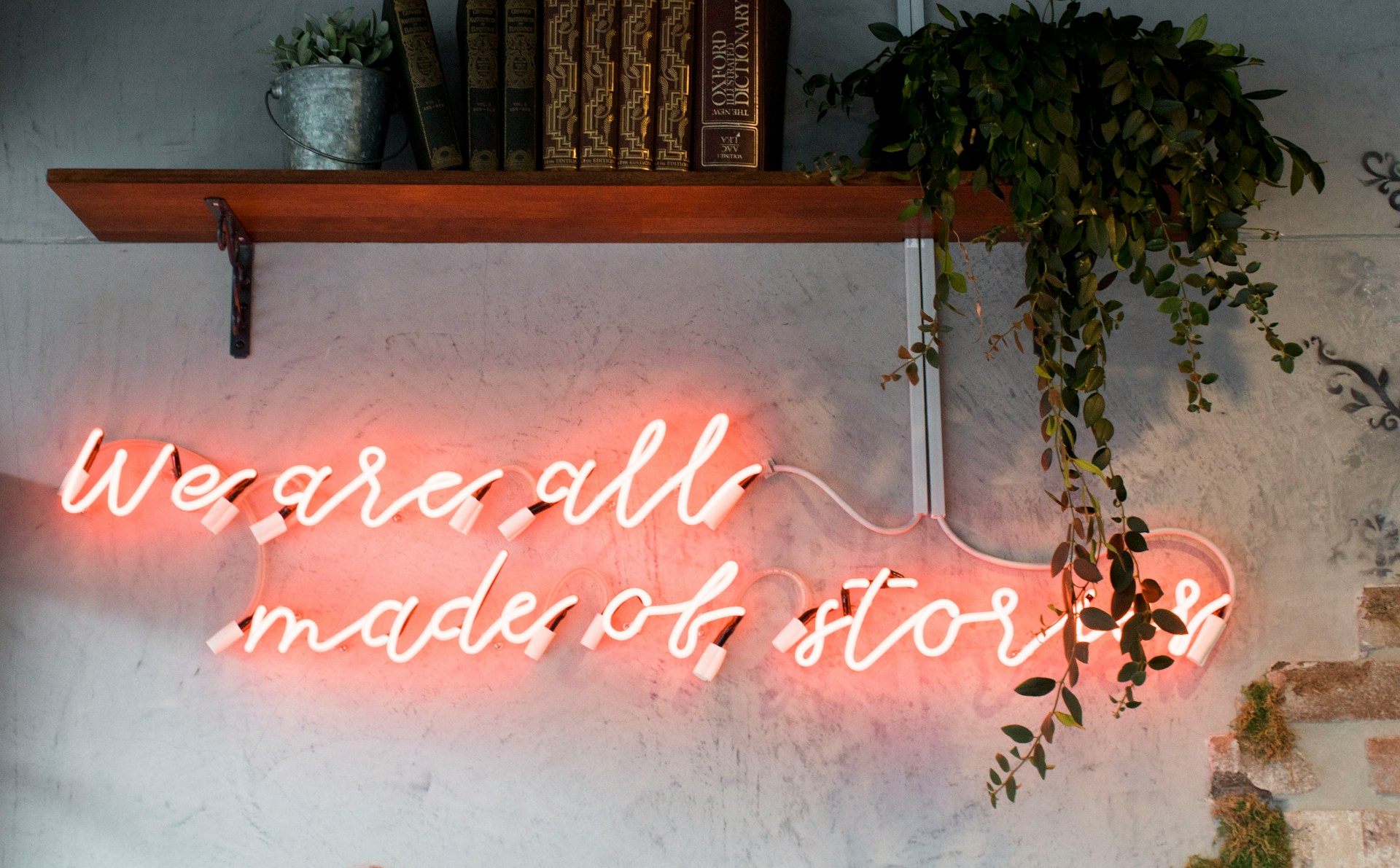 neon sign under a bookshelf on the wall