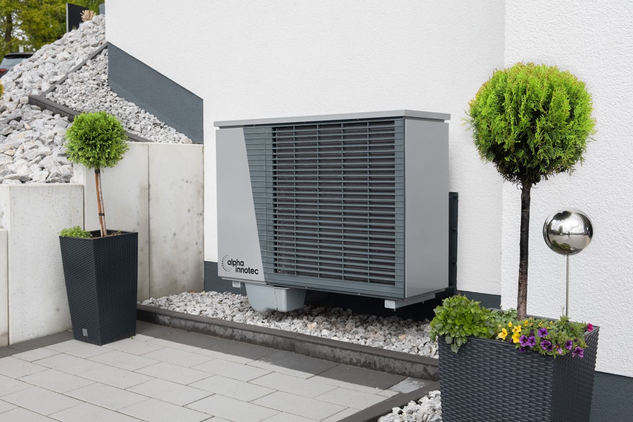 Trees and air conditioner by building wall. Image by Pexels