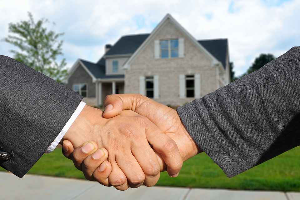 people shaking hands in front of a house