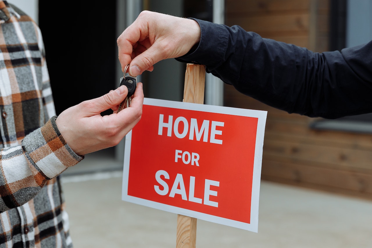 Person getting keys, home for sale sign