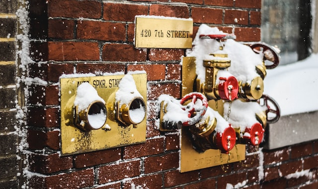 pipes, snow on a brick building