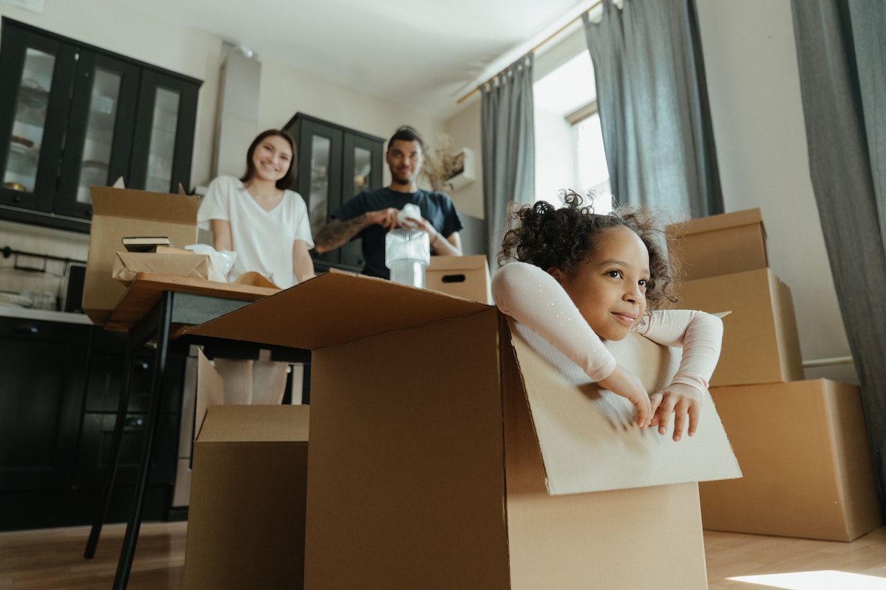 child in a box, parent in the backgroun unpacking boxes