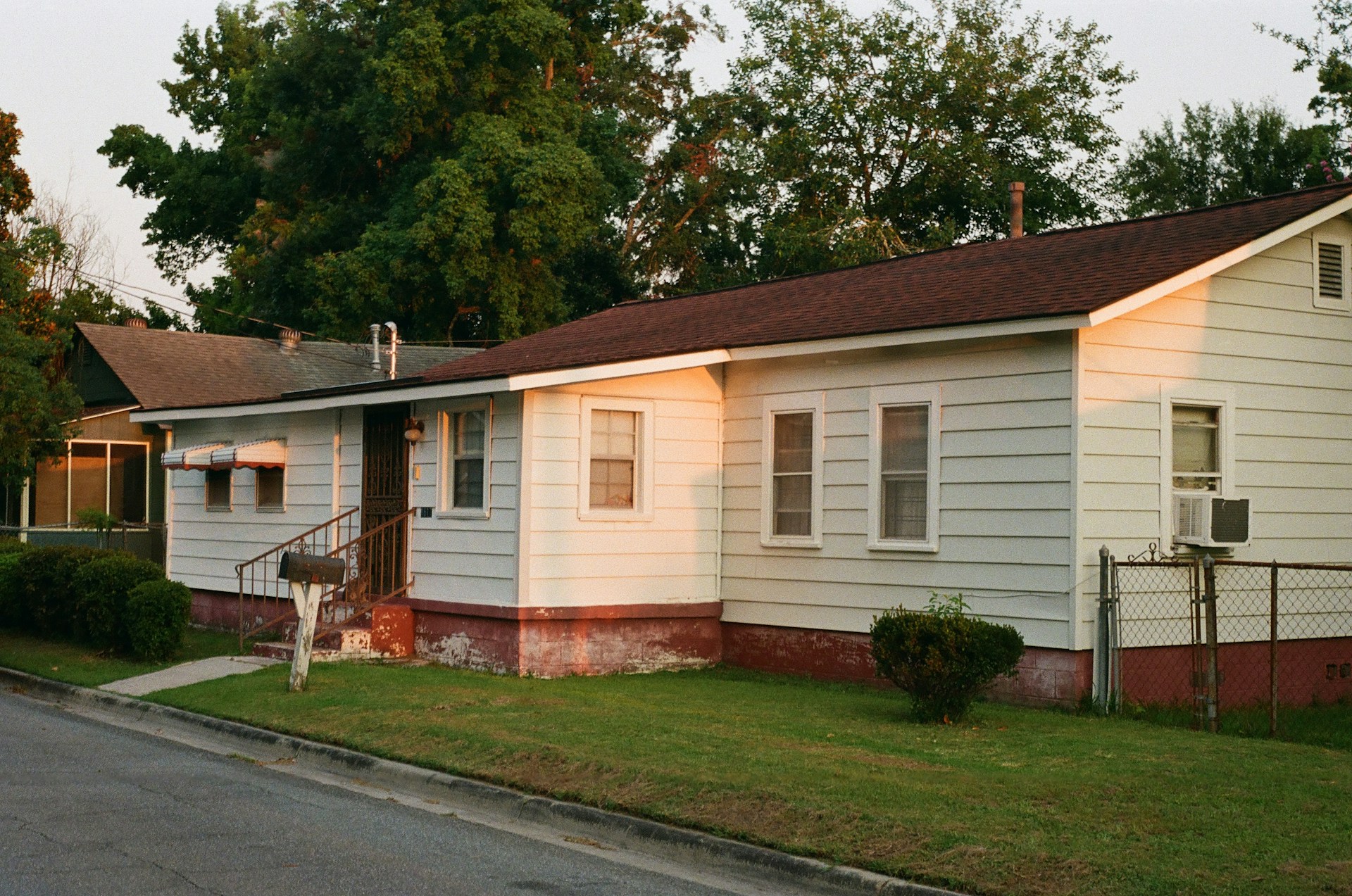 White and brown house. Trees in the background. Image by Unsplash