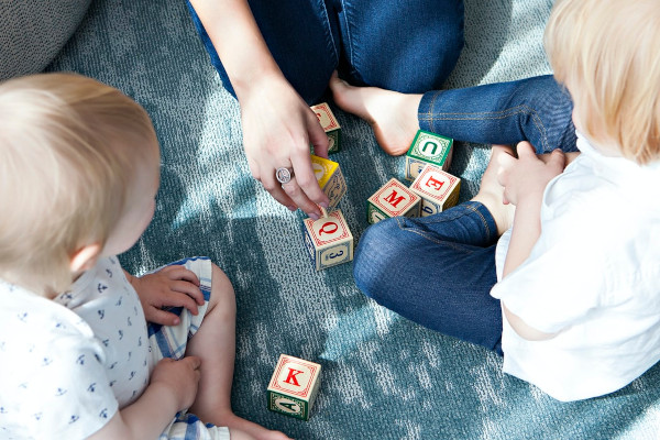 Two toddlers playing with letter cubes.