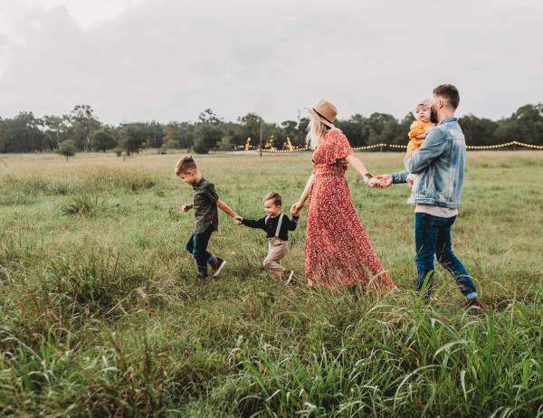 Five people walking through a grass field holding hands.