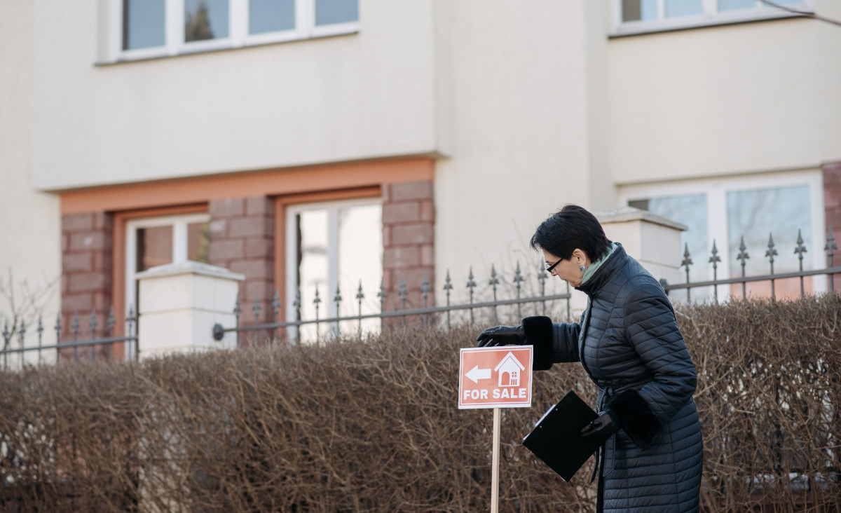 person in front of a for sale sign