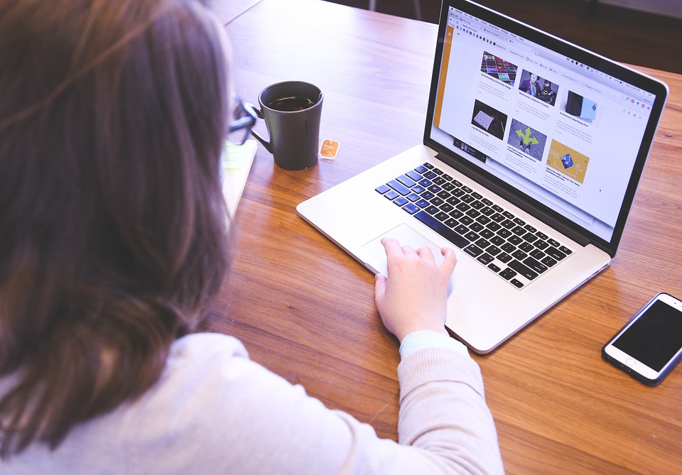 person sitting at table with a laptop and phone