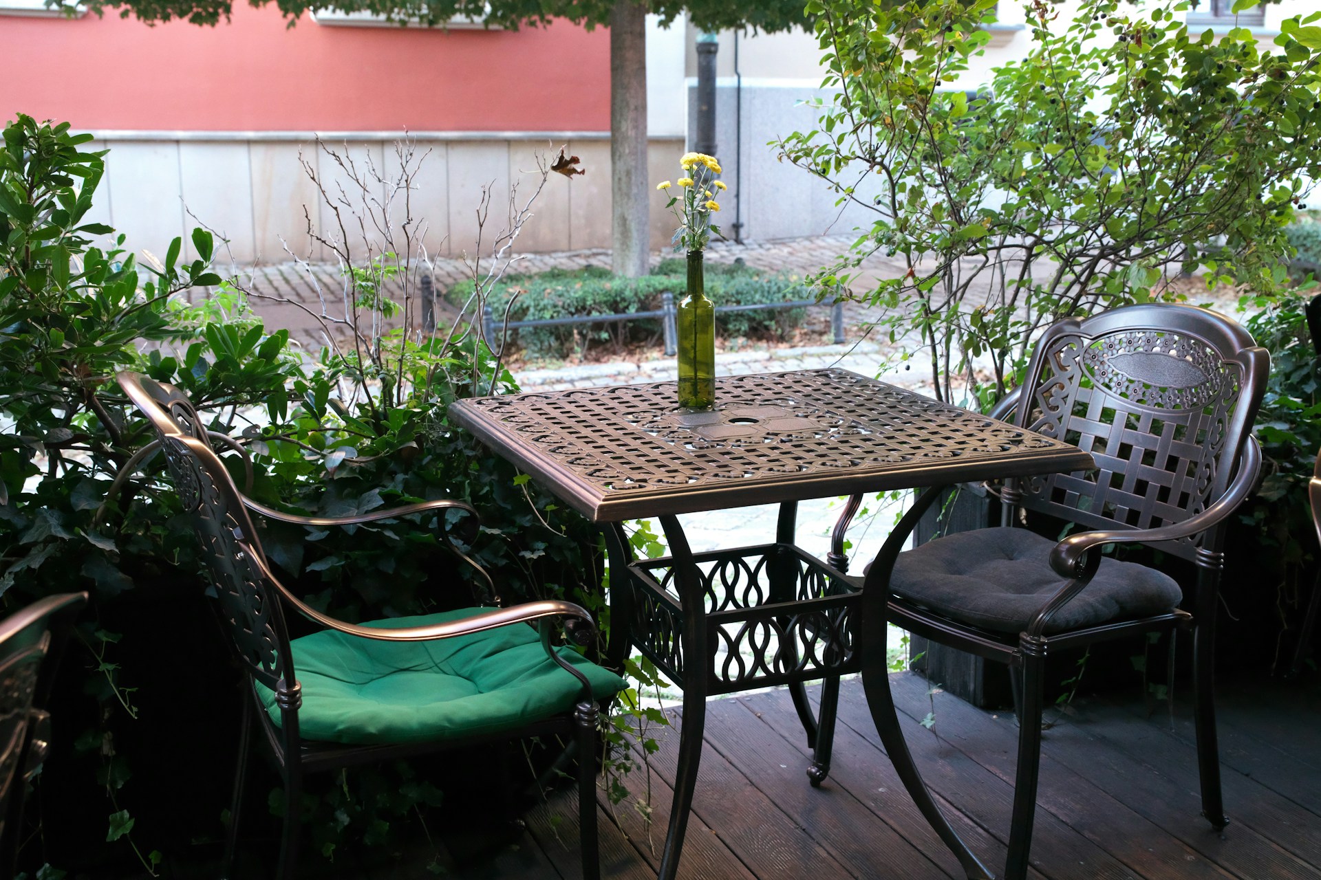 Table and chairs on a patio with greenery. Image by Unsplash