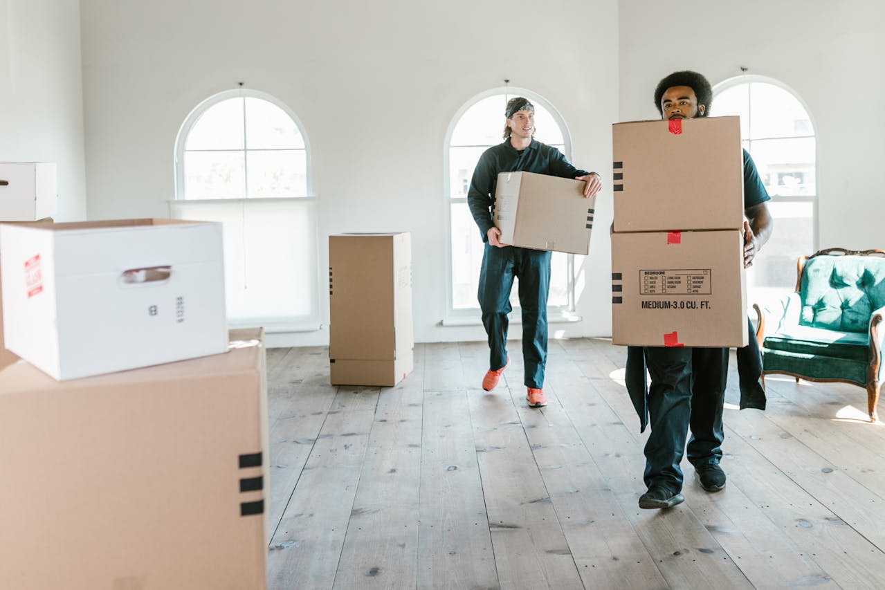 People carrying boxes inside a house. Image by Pexels