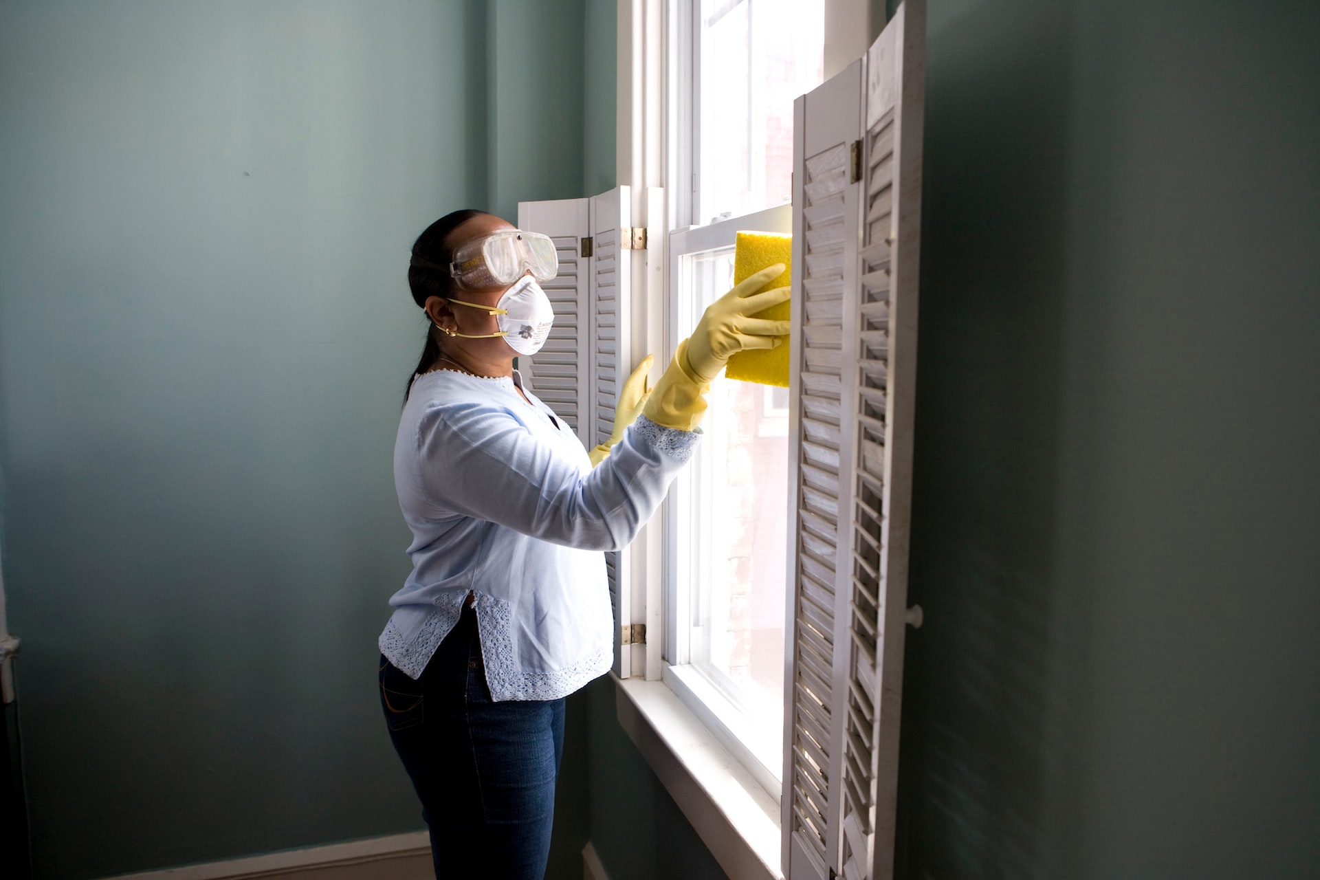 person with a mask and googles cleaning a window