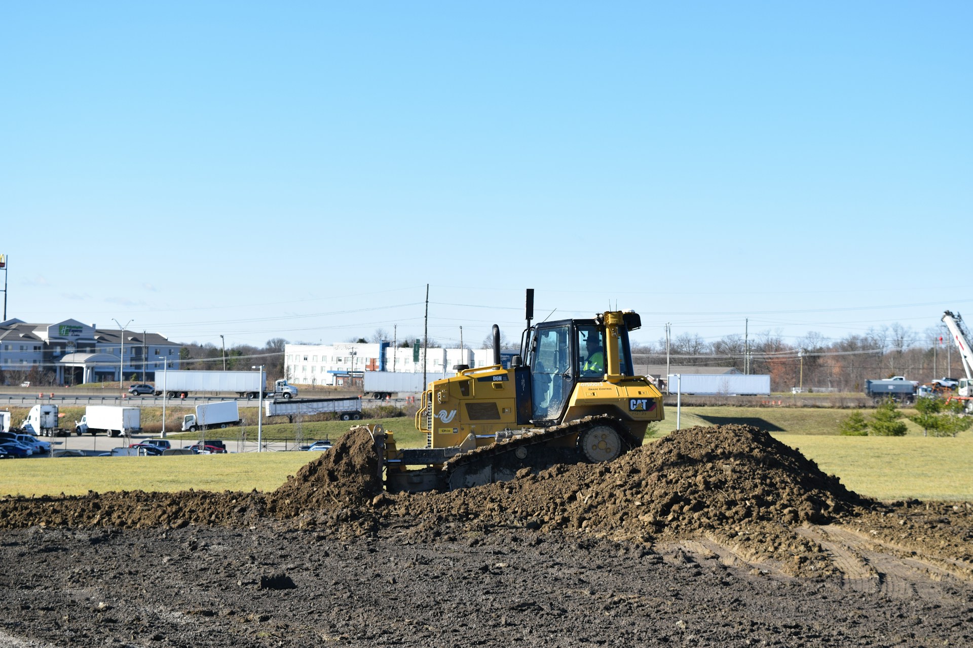 bulldozer digging through a pile of dirt - Image by by Corey Willett Unsplash