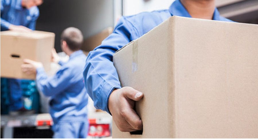 Movers carrying moving boxes, unloading a truck.