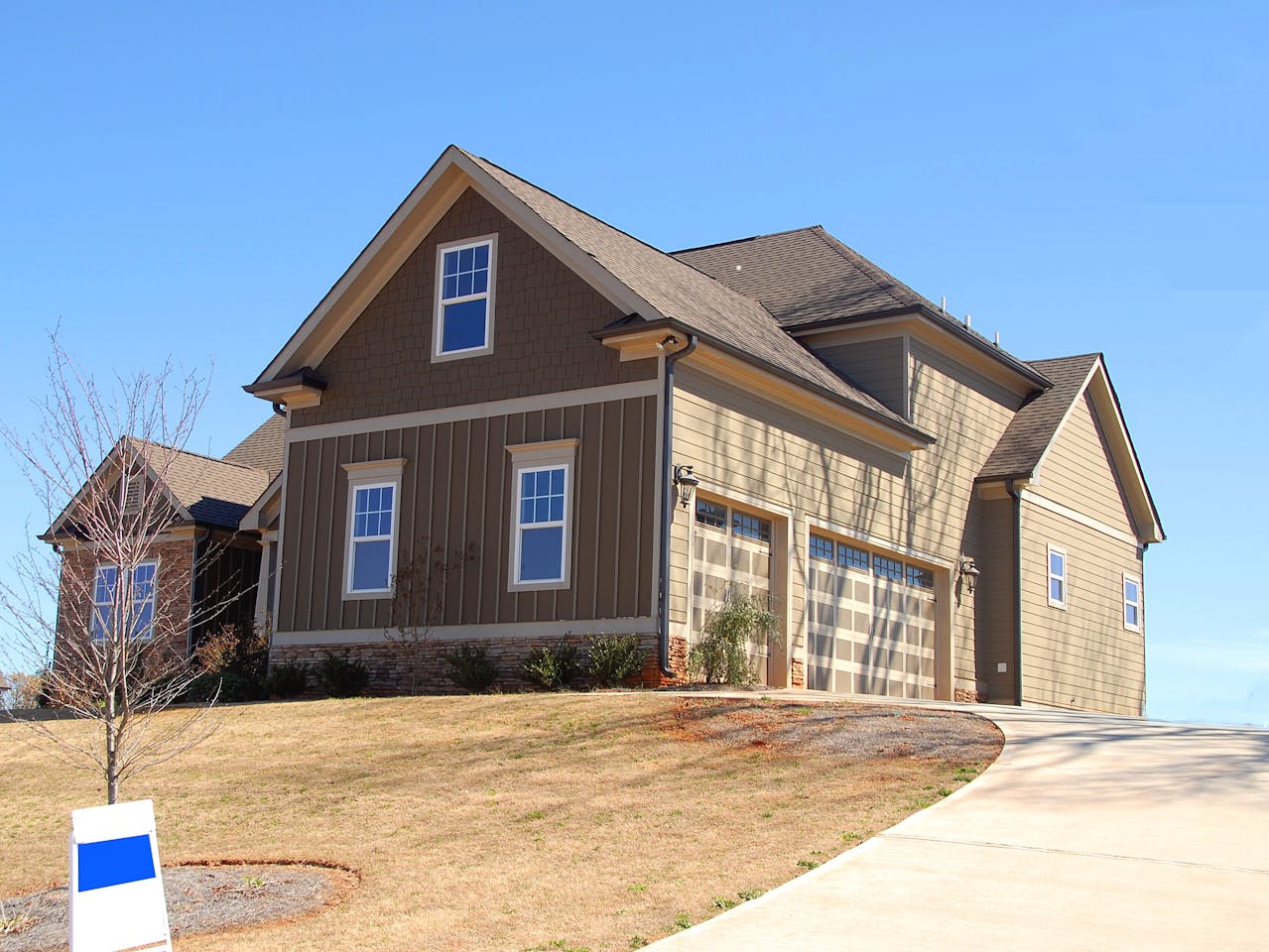 A brown and beige wooden house with a clean roof under a blue sky. Image by Pexels