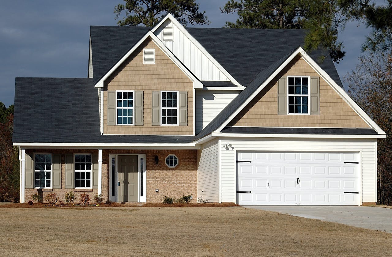 White and tan brick and wood house. Yellow lawn. Image by Pexels
