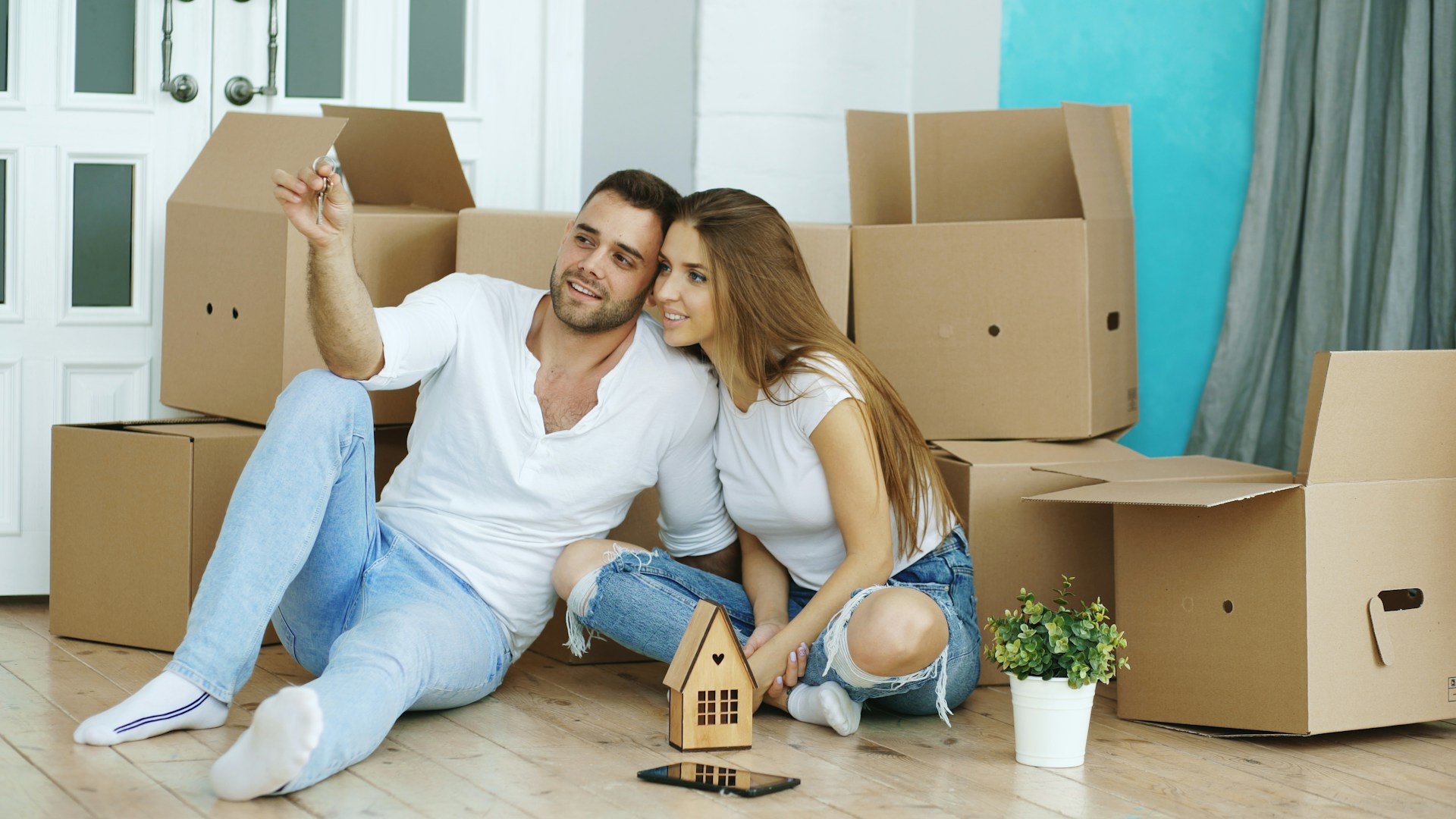 Couple sitting on floor surrounded by moving boxes. Image by Unsplash