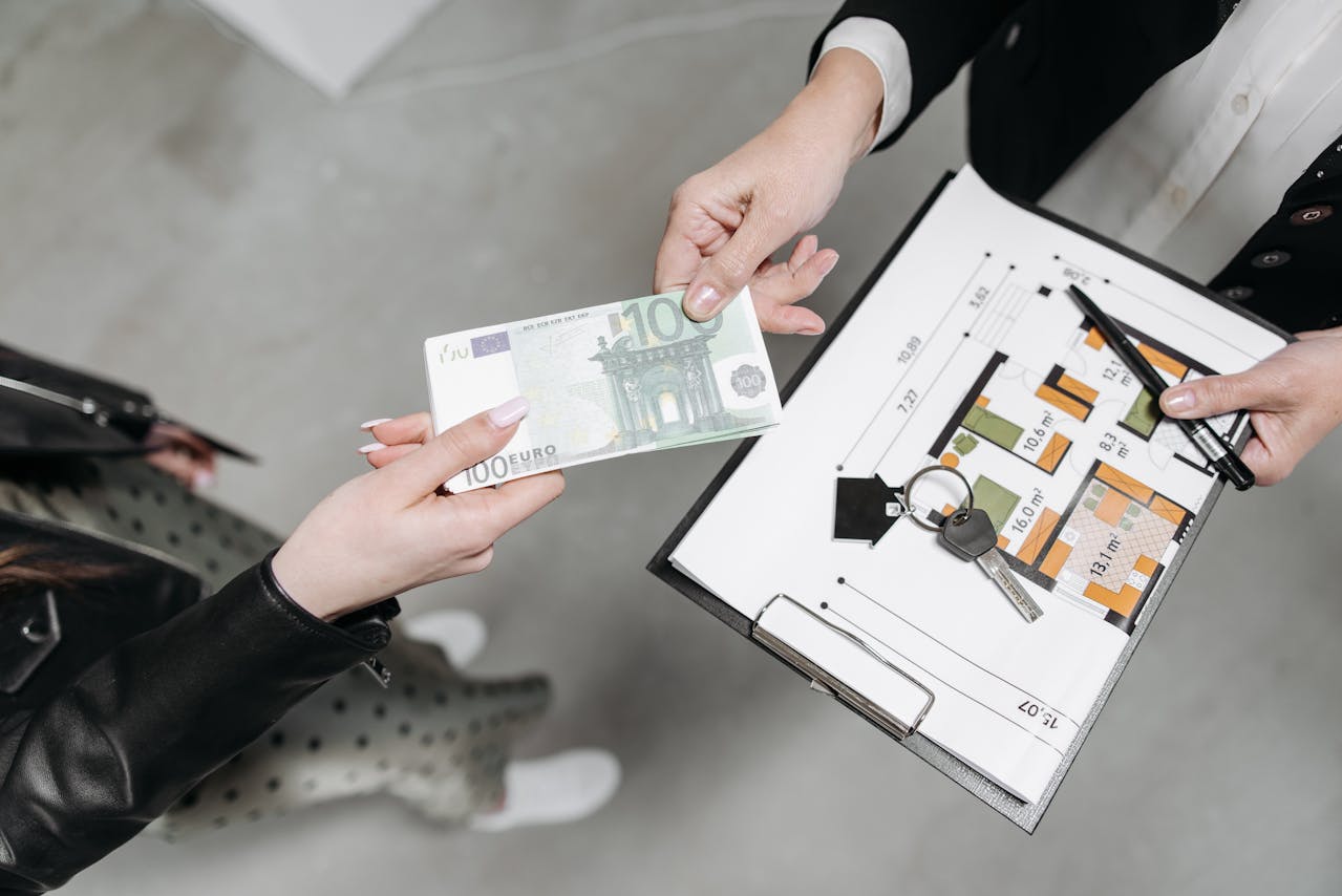 A client handing money to a realtor. Image by Pexels