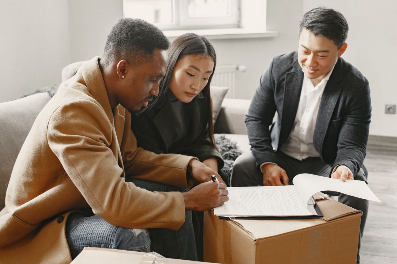 A couple sitting on a sofa with a broker. Image by Pexels