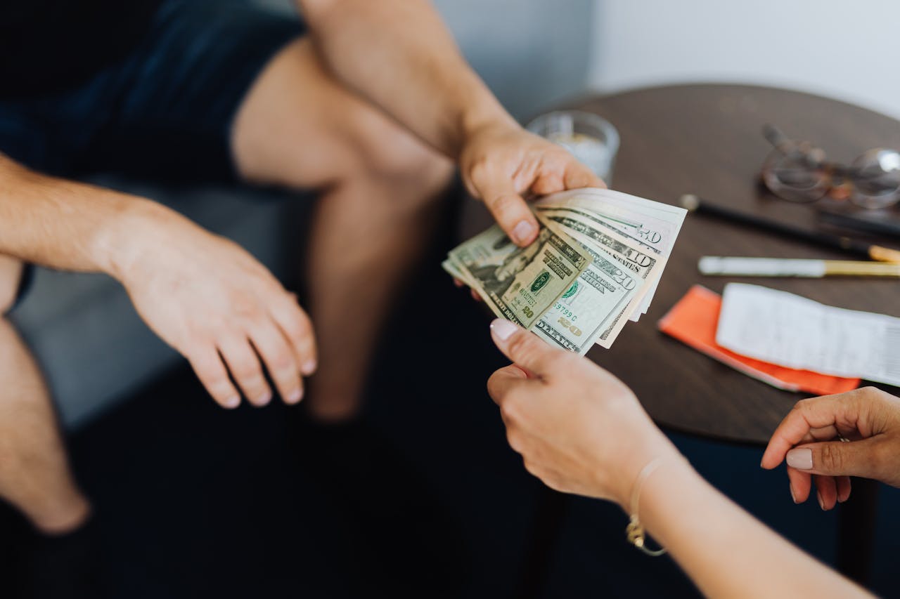 Person giving money to someone. Image by Pexels