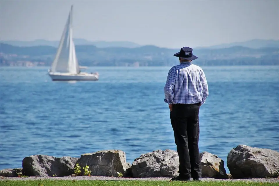 person looking out on the ocean, sailboat