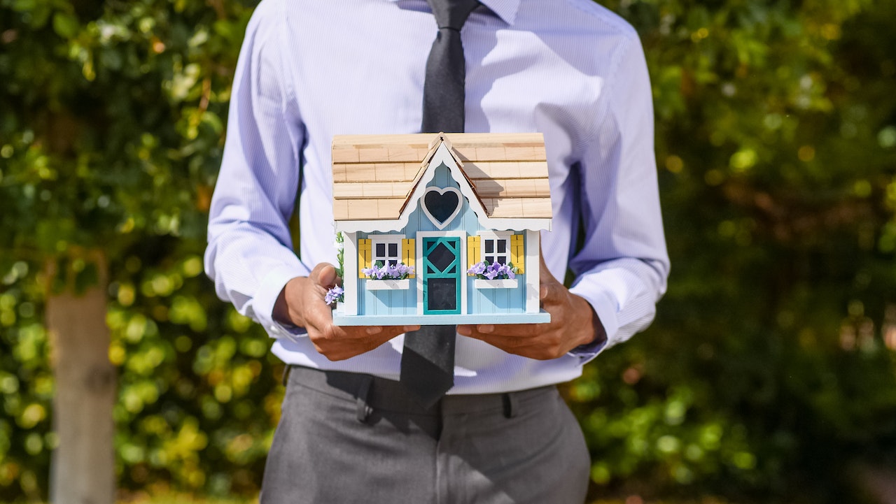 person hiding a house in his hands